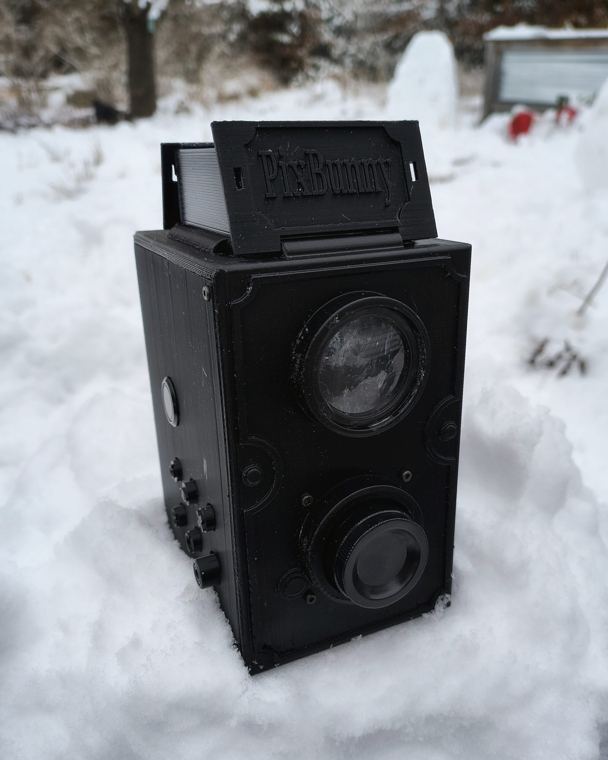 A dual lens reflex style camera, sitting in the snow.